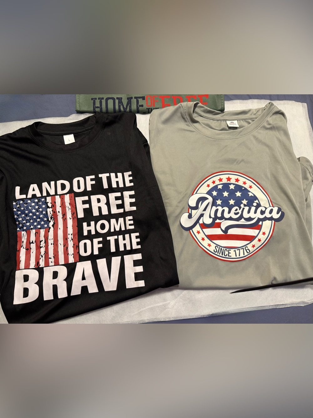 2 American t-shirts. Sz. L . Black and Gray (unisex) & home of the free bag.